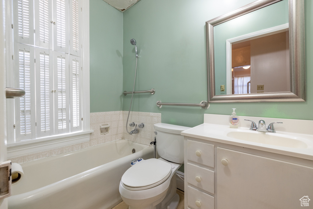 Bathroom with vanity with extensive cabinet space, plenty of natural light, and toilet