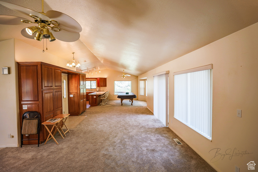 Interior space featuring ceiling fan with notable chandelier, pool table, carpet floors, and lofted ceiling