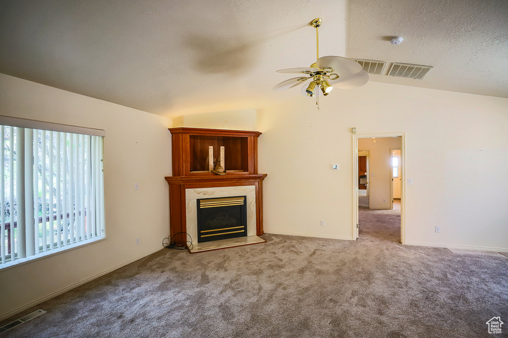 Unfurnished living room with carpet floors, ceiling fan, vaulted ceiling, and a fireplace