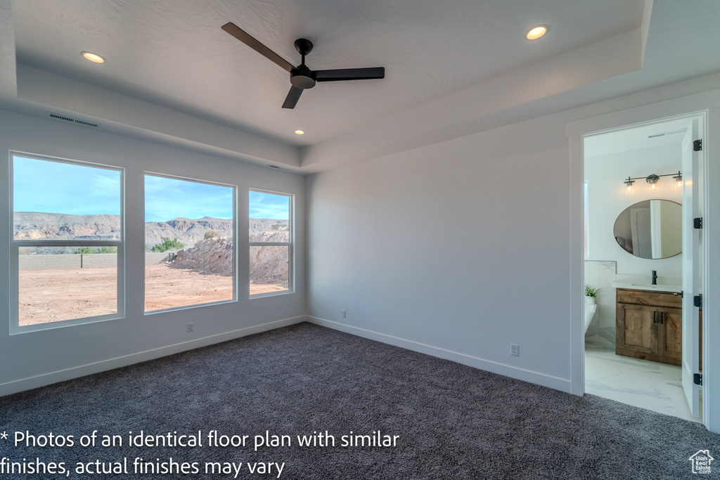 Empty room with tile floors, ceiling fan, sink, and a tray ceiling