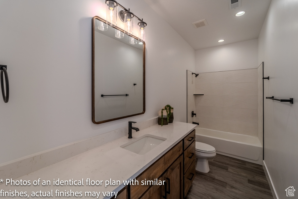 Full bathroom featuring hardwood / wood-style floors, vanity, tiled shower / bath combo, and toilet