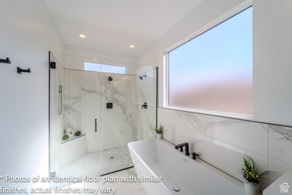 Bathroom with a wealth of natural light, tile floors, independent shower and bath, and tile walls