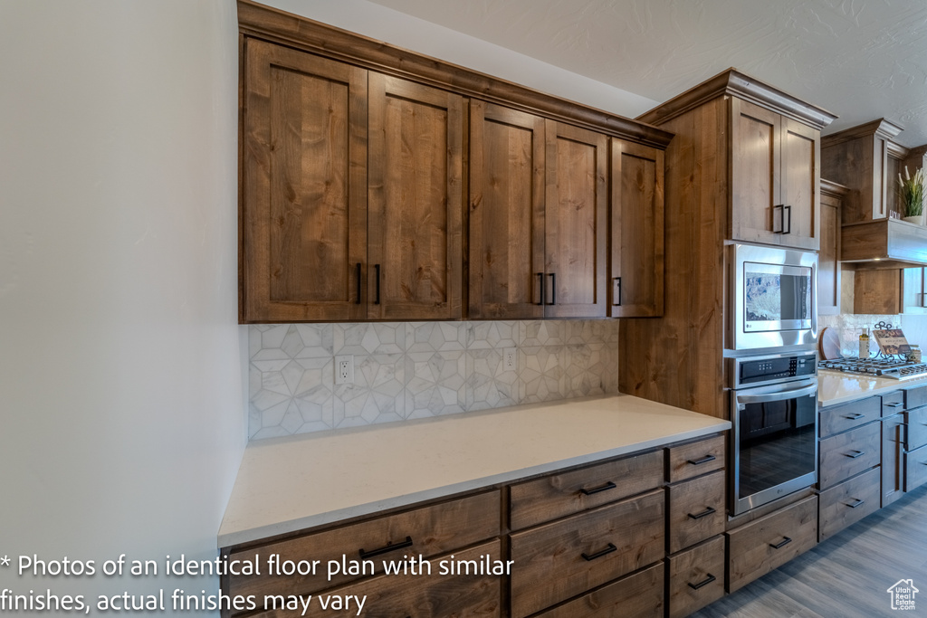 Kitchen with appliances with stainless steel finishes, tasteful backsplash, and light hardwood / wood-style flooring