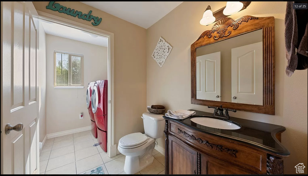 Bathroom with vanity with extensive cabinet space, tile floors, toilet, and washing machine and dryer