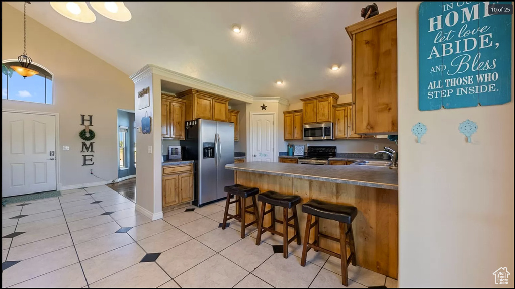 Kitchen with hanging light fixtures, sink, stainless steel appliances, and light tile floors