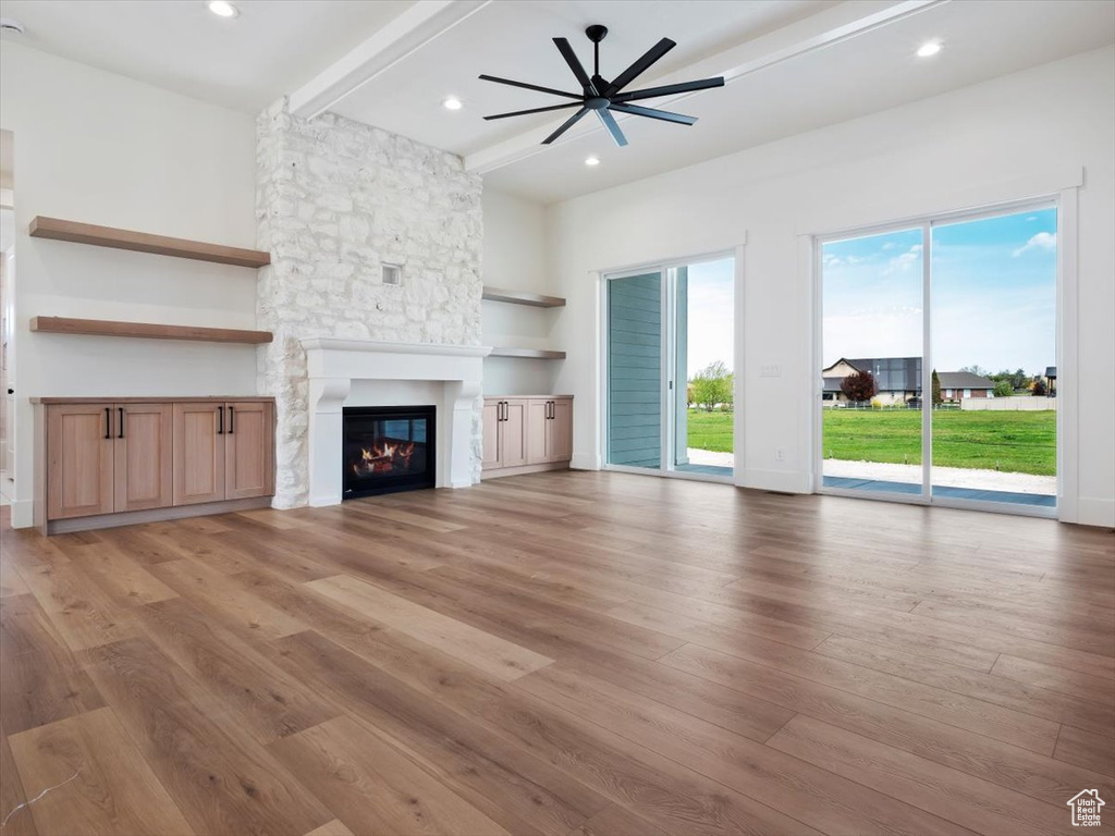 Unfurnished living room with beamed ceiling, ceiling fan, hardwood / wood-style flooring, and a fireplace