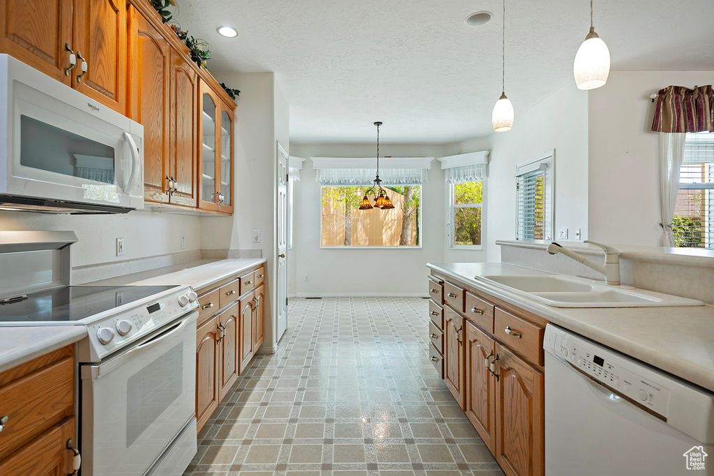 Kitchen with a healthy amount of sunlight, sink, white appliances, and light tile flooring