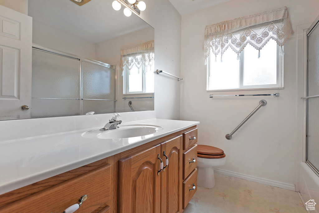 Full bathroom with tile floors, combined bath / shower with glass door, vanity, and toilet