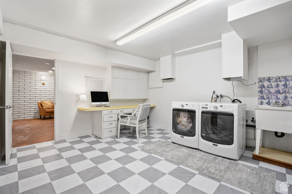 Laundry room with brick wall, sink, light tile flooring, and washer and clothes dryer