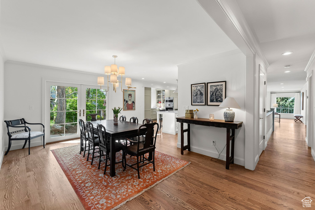 Dining room featuring a wealth of natural light, ornamental molding, and light hardwood / wood-style flooring