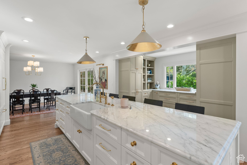 Kitchen with sink, a center island with sink, hanging light fixtures, and light hardwood / wood-style flooring