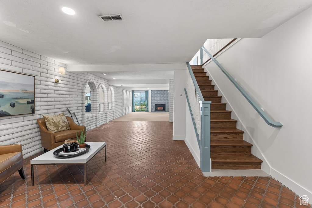 Stairs with brick wall and dark tile flooring