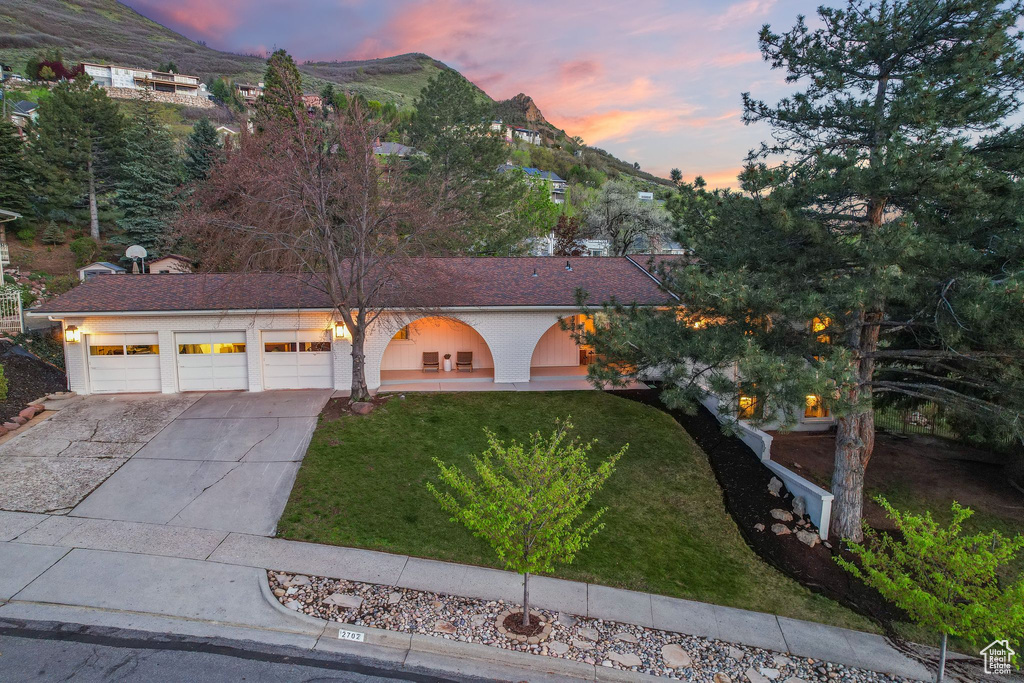 View of front of house with a garage, a mountain view, and a yard