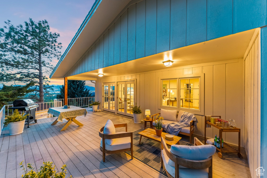 Deck at dusk featuring an outdoor living space, french doors, and a grill