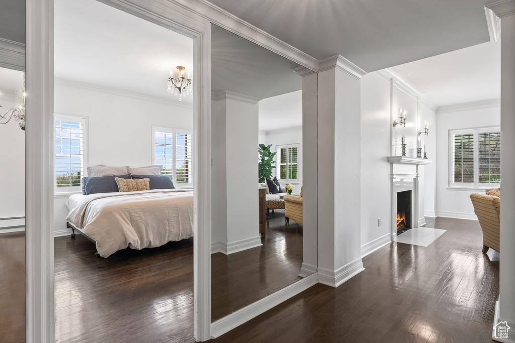 Bedroom featuring crown molding, ornate columns, dark hardwood / wood-style floors, and an inviting chandelier