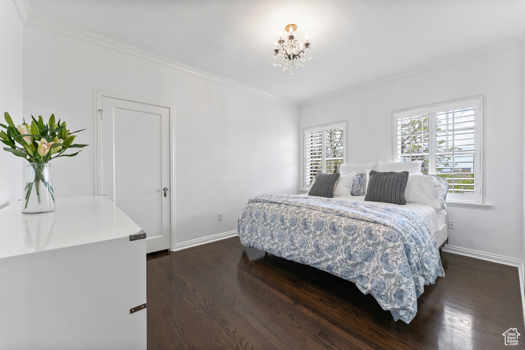 Bedroom featuring ornamental molding, dark hardwood / wood-style flooring, and an inviting chandelier