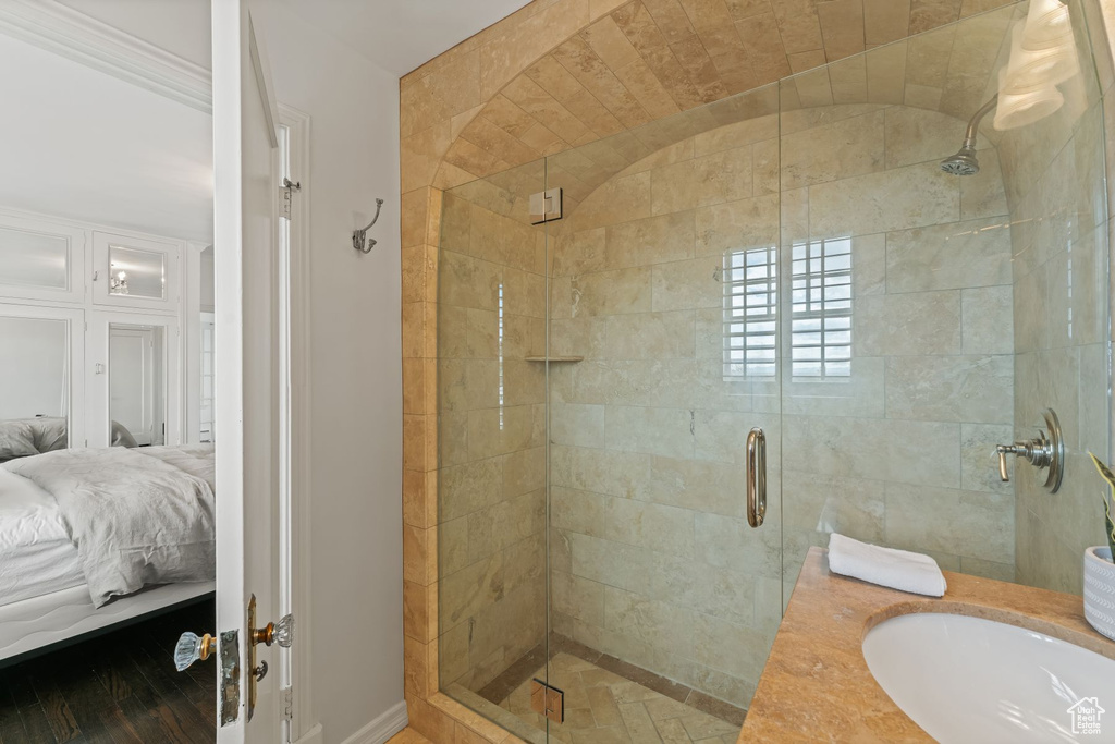 Bathroom featuring sink, a shower with shower door, hardwood / wood-style flooring, and ornamental molding