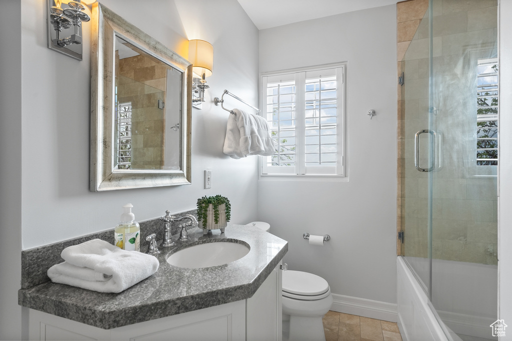 Full bathroom with toilet, tile flooring, vanity, and combined bath / shower with glass door