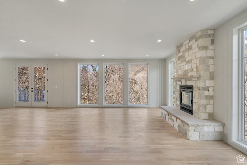 Unfurnished living room featuring french doors, light hardwood / wood-style flooring, and a fireplace