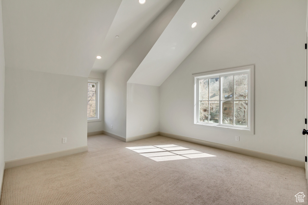 Additional living space with vaulted ceiling and light carpet