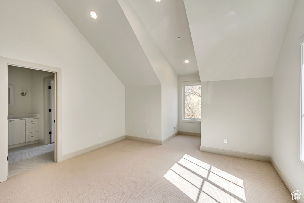 Bonus room with light colored carpet and vaulted ceiling