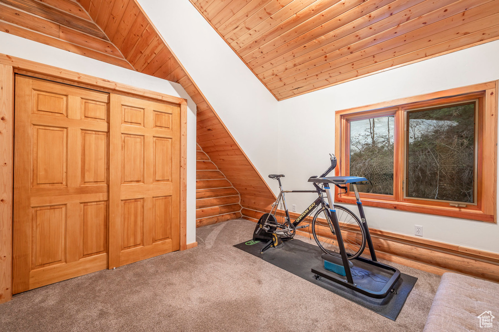 Exercise room featuring wooden ceiling, vaulted ceiling, and carpet flooring