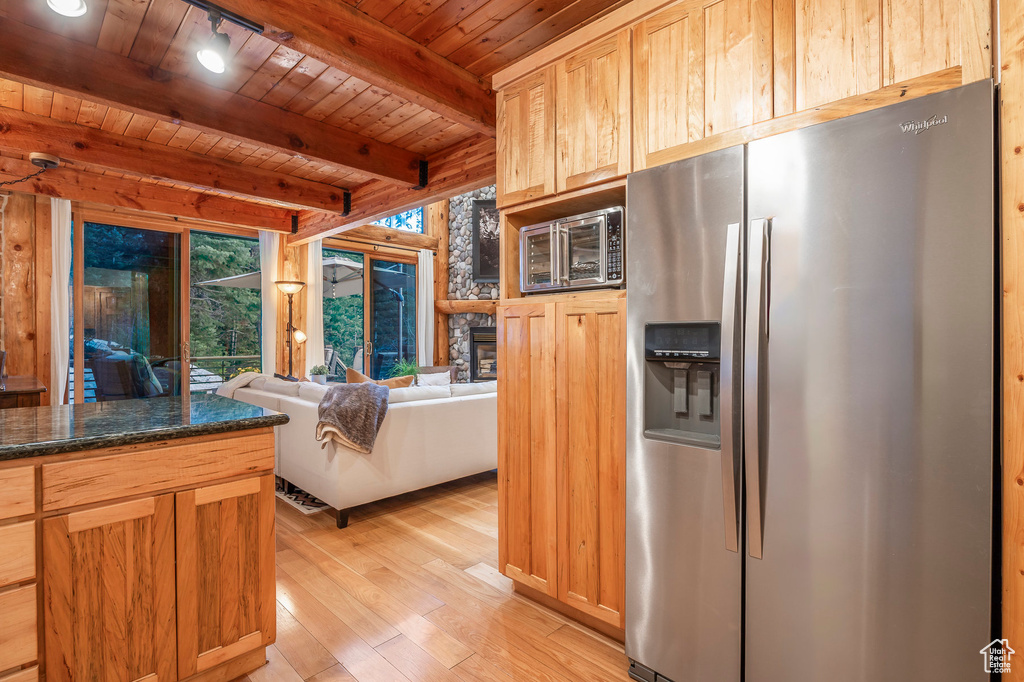 Kitchen featuring beamed ceiling, a fireplace, wooden ceiling, light hardwood / wood-style flooring, and stainless steel refrigerator with ice dispenser