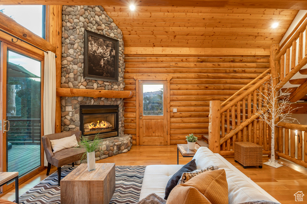 Living room with hardwood / wood-style floors, log walls, a fireplace, and a wealth of natural light