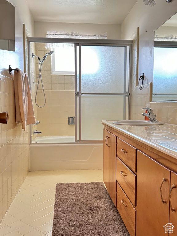 Bathroom featuring vanity, combined bath / shower with glass door, and tile flooring