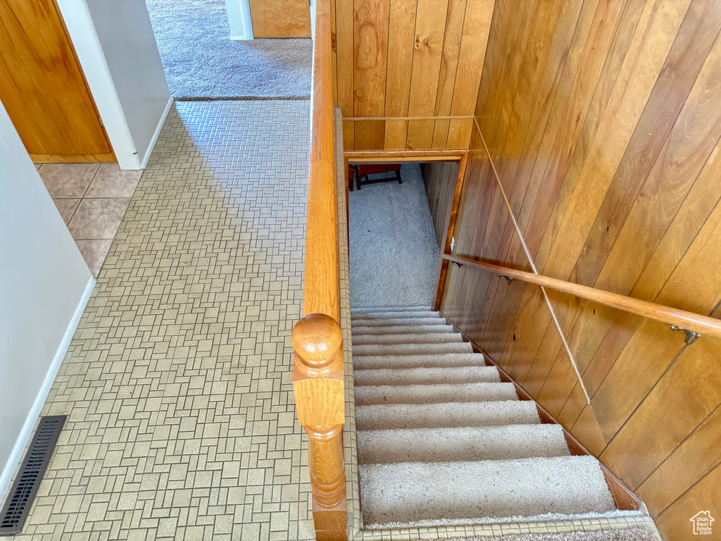 Staircase featuring tile flooring and wood walls