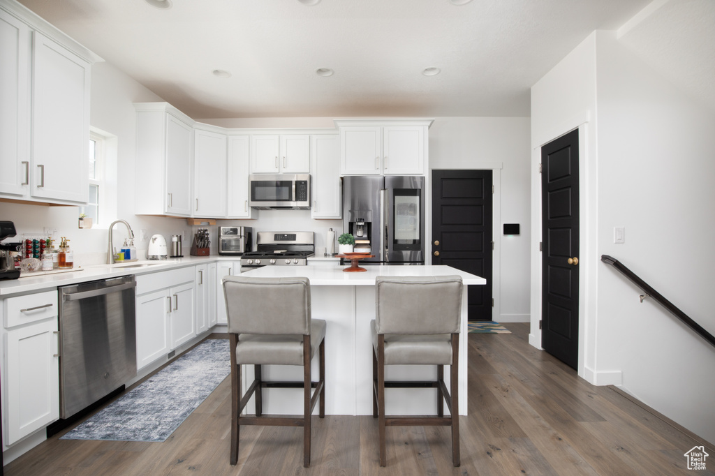 Kitchen with a kitchen island, sink, stainless steel appliances, and dark wood-type flooring