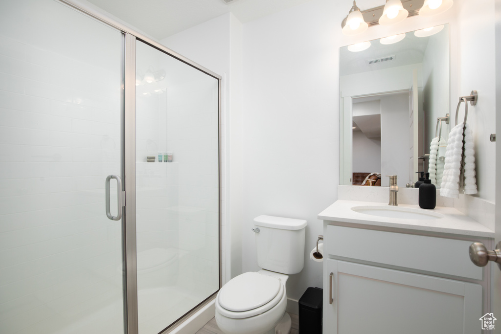 Bathroom featuring oversized vanity, a shower with shower door, and toilet