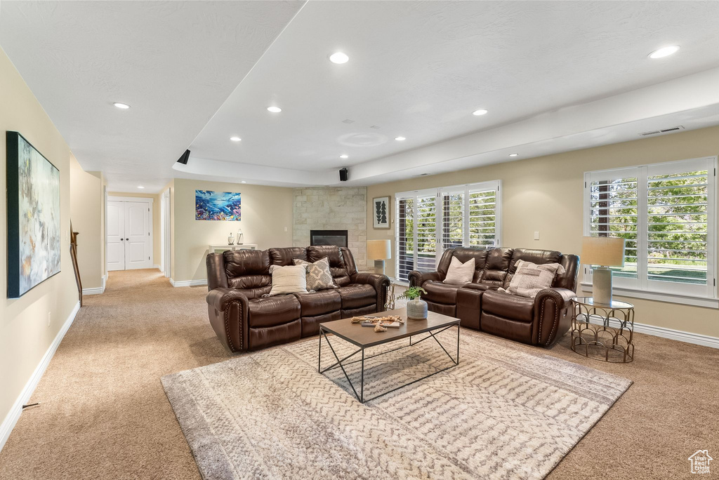 Carpeted living room featuring a raised ceiling and a fireplace
