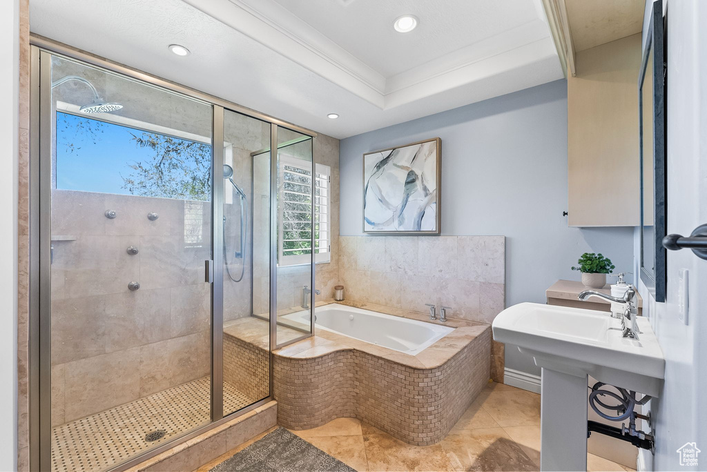 Bathroom featuring a tray ceiling, ornamental molding, tile floors, and separate shower and tub