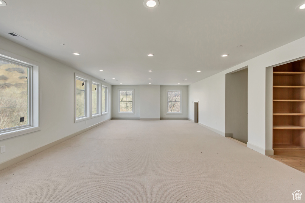 Unfurnished room featuring light carpet and built in features