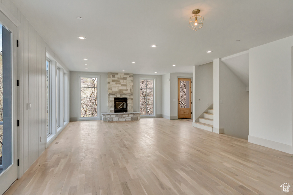 Unfurnished living room featuring light hardwood / wood-style floors and a stone fireplace