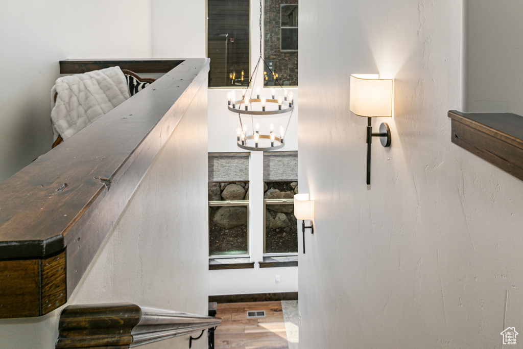 Stairway with wood-type flooring and an inviting chandelier