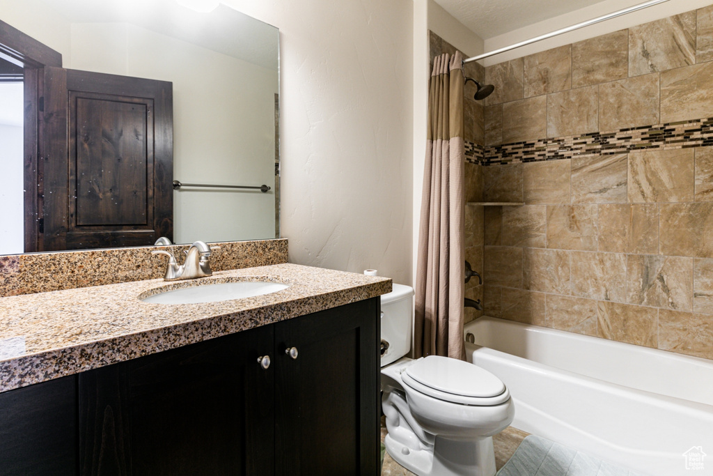 Full bathroom featuring shower / tub combo with curtain, vanity, tile floors, and toilet