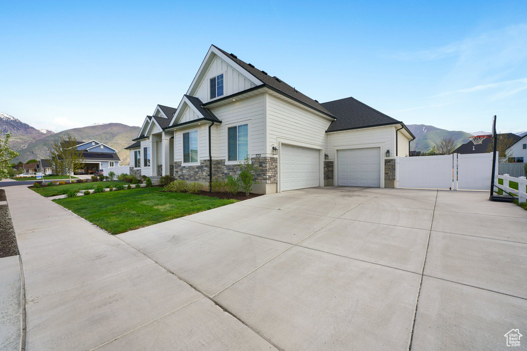 View of front of home featuring a garage, a mountain view, and a front lawn