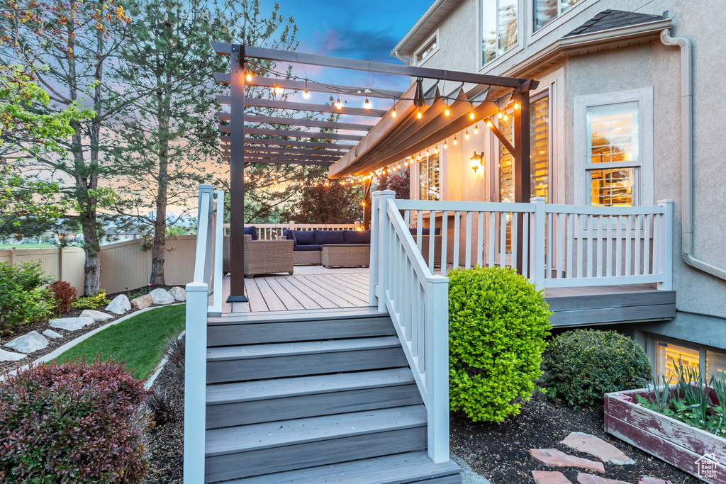 Deck at dusk with outdoor lounge area and a pergola