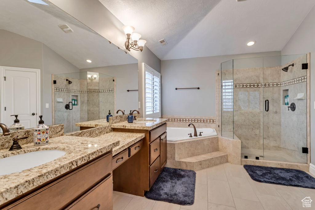 Bathroom with double sink vanity, tile floors, a notable chandelier, and plus walk in shower