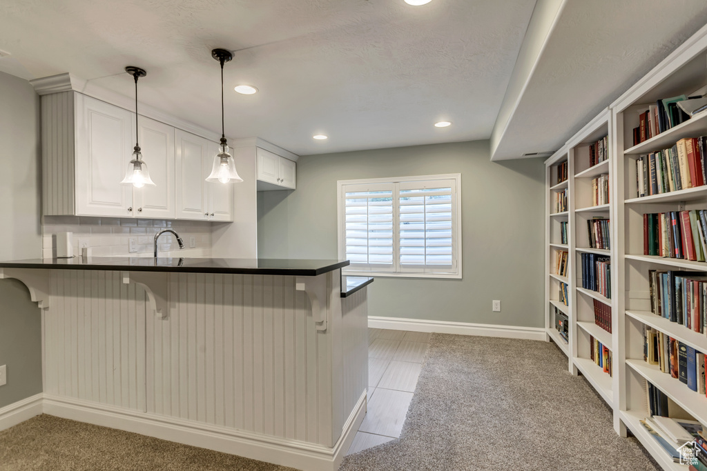 Kitchen with white cabinetry, kitchen peninsula, light carpet, and a breakfast bar