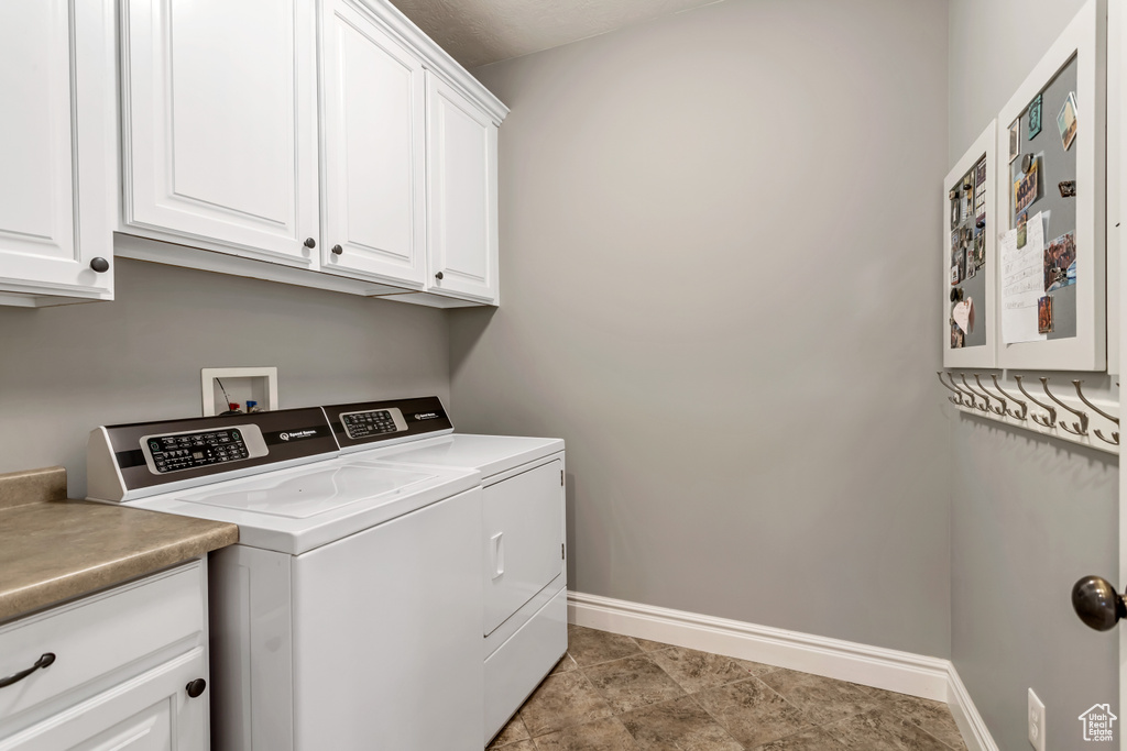 Laundry room featuring cabinets, hookup for a washing machine, light tile flooring, and washer and clothes dryer