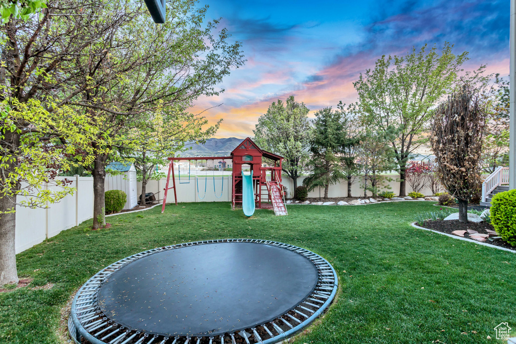 Yard at dusk with a playground and a trampoline