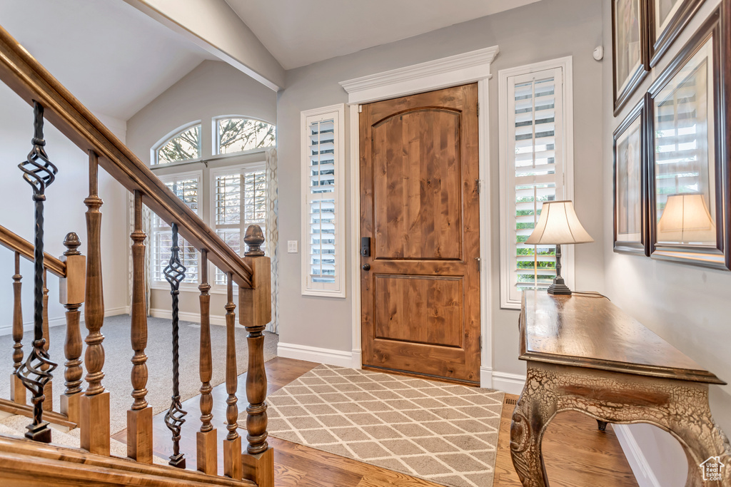 Foyer entrance featuring plenty of natural light, vaulted ceiling, and hardwood / wood-style flooring
