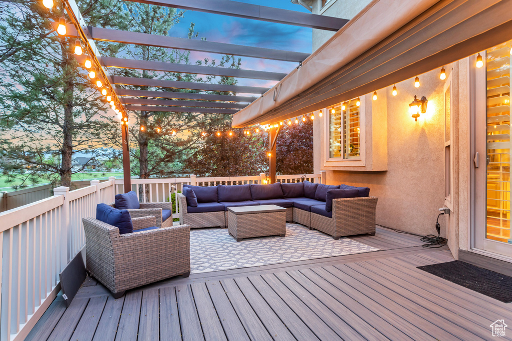 Deck at dusk with an outdoor living space and a pergola