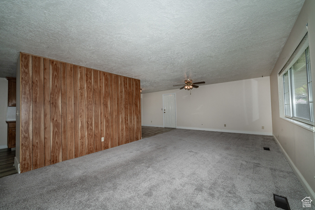 Unfurnished living room with a textured ceiling, ceiling fan, and carpet flooring
