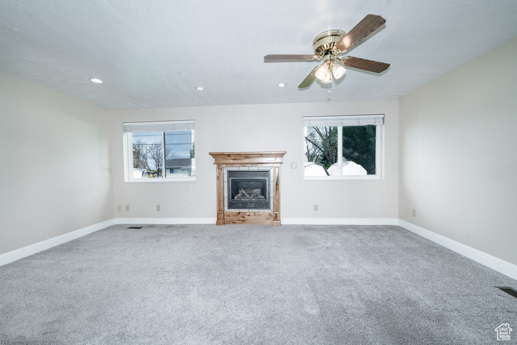Unfurnished living room featuring plenty of natural light, carpet floors, and ceiling fan