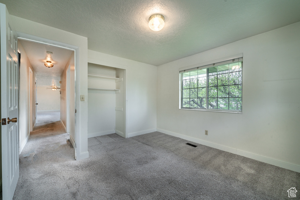 Unfurnished bedroom featuring a closet, carpet flooring, and a textured ceiling