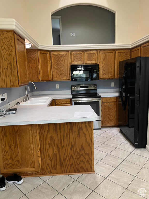 Kitchen featuring sink, kitchen peninsula, light tile floors, and black appliances